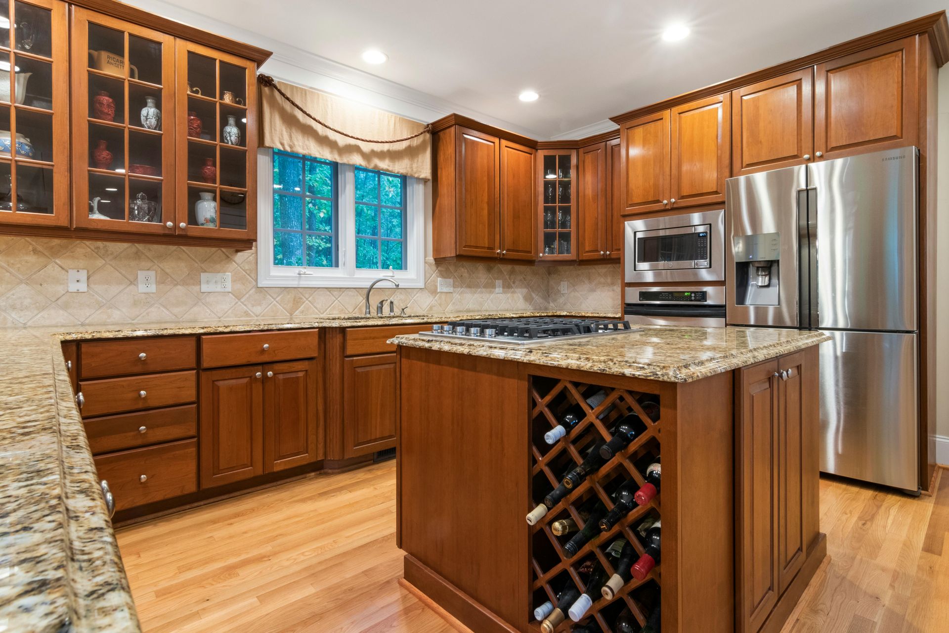 Warm cherry wood kitchen cabinets with granite counters and an island wine rack