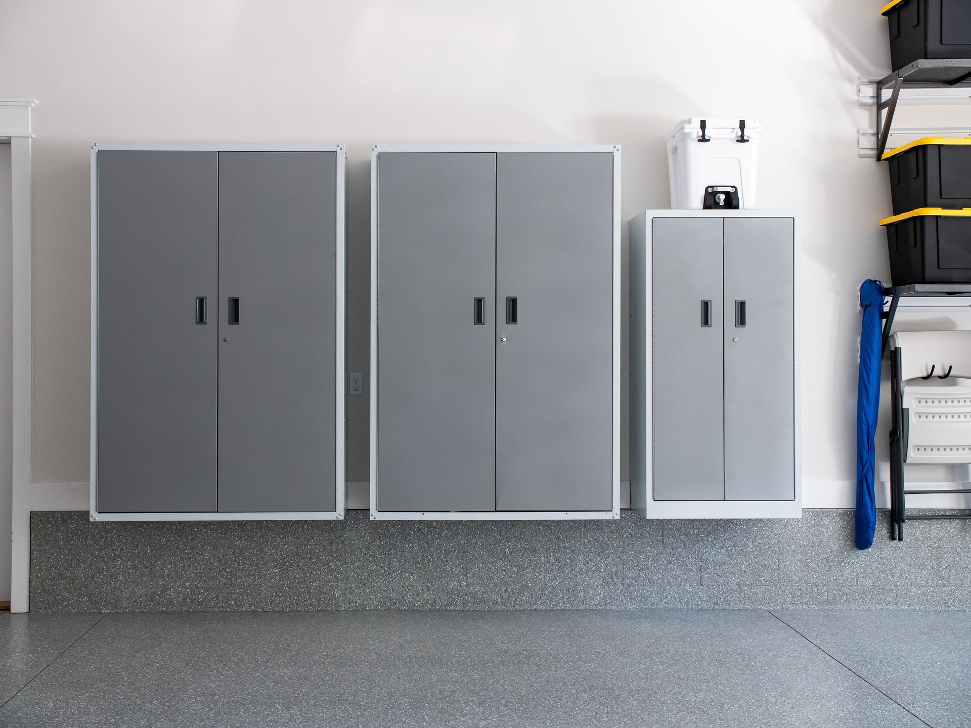 Grey heavy duty garage storage cabinets mounted along a wall above an epoxy floor