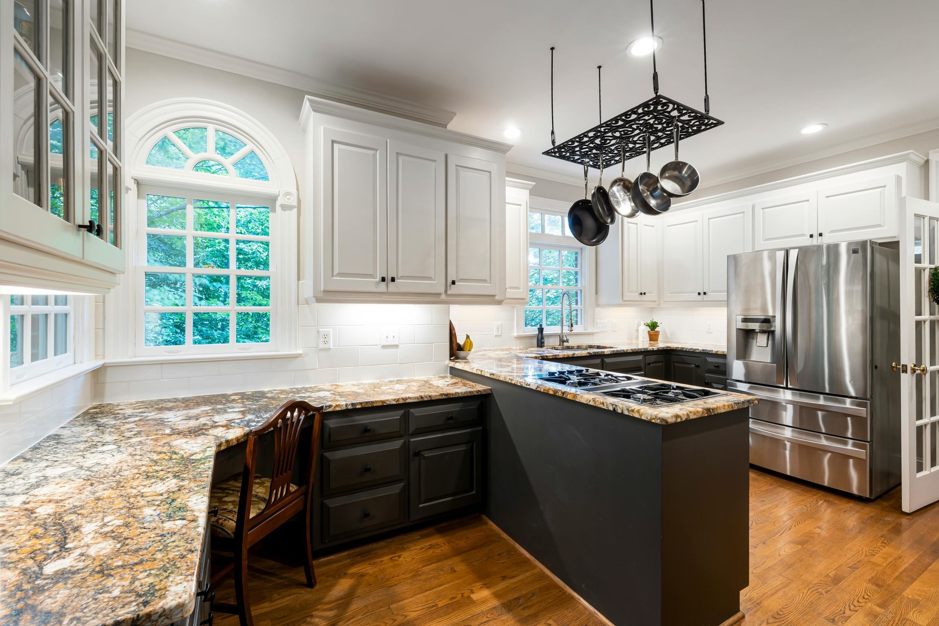 White kitchen cabinets with a dark painted peninsula and patterned granite countertops