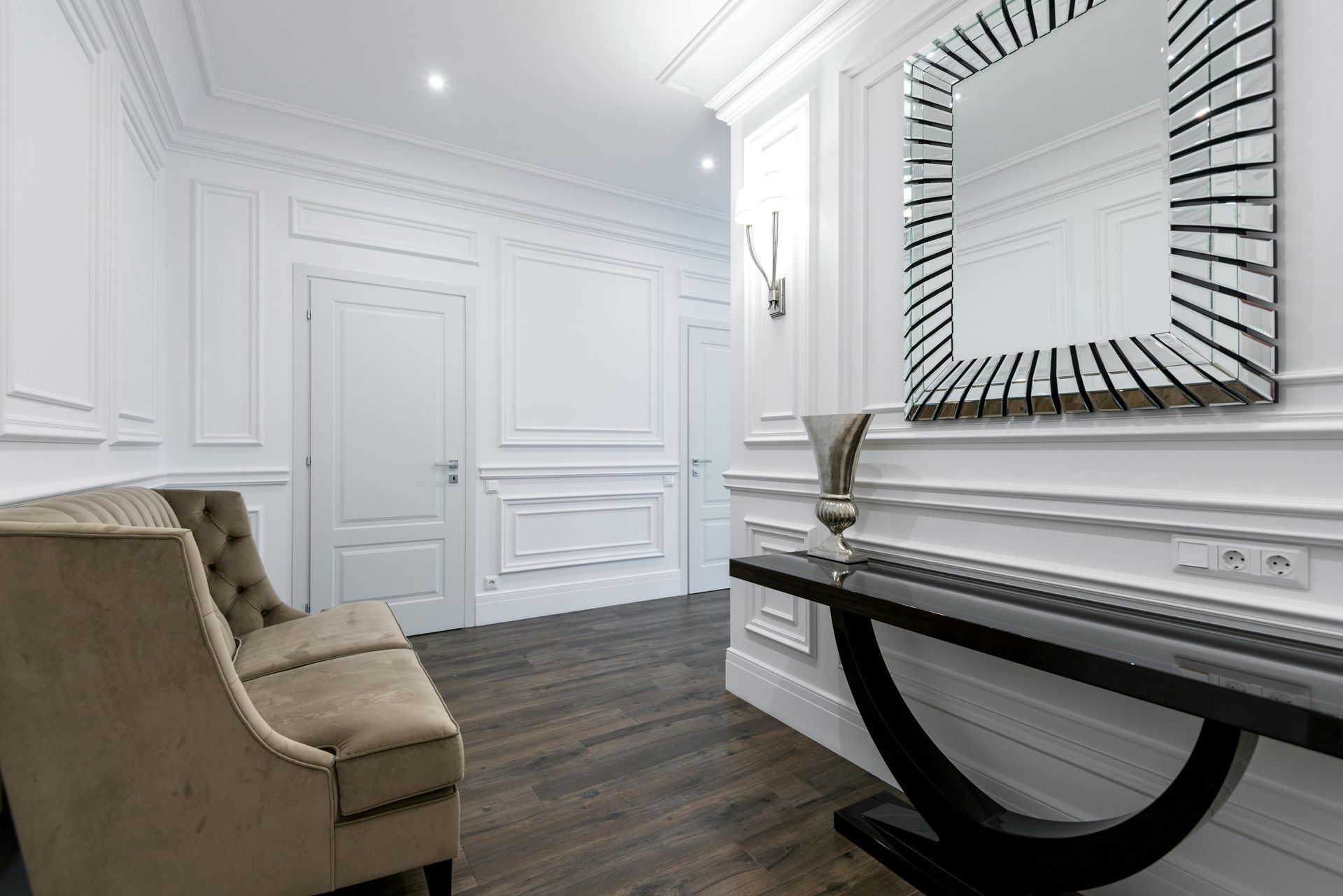 Hallway with white panelled walls, detailed mouldings and a dark console table