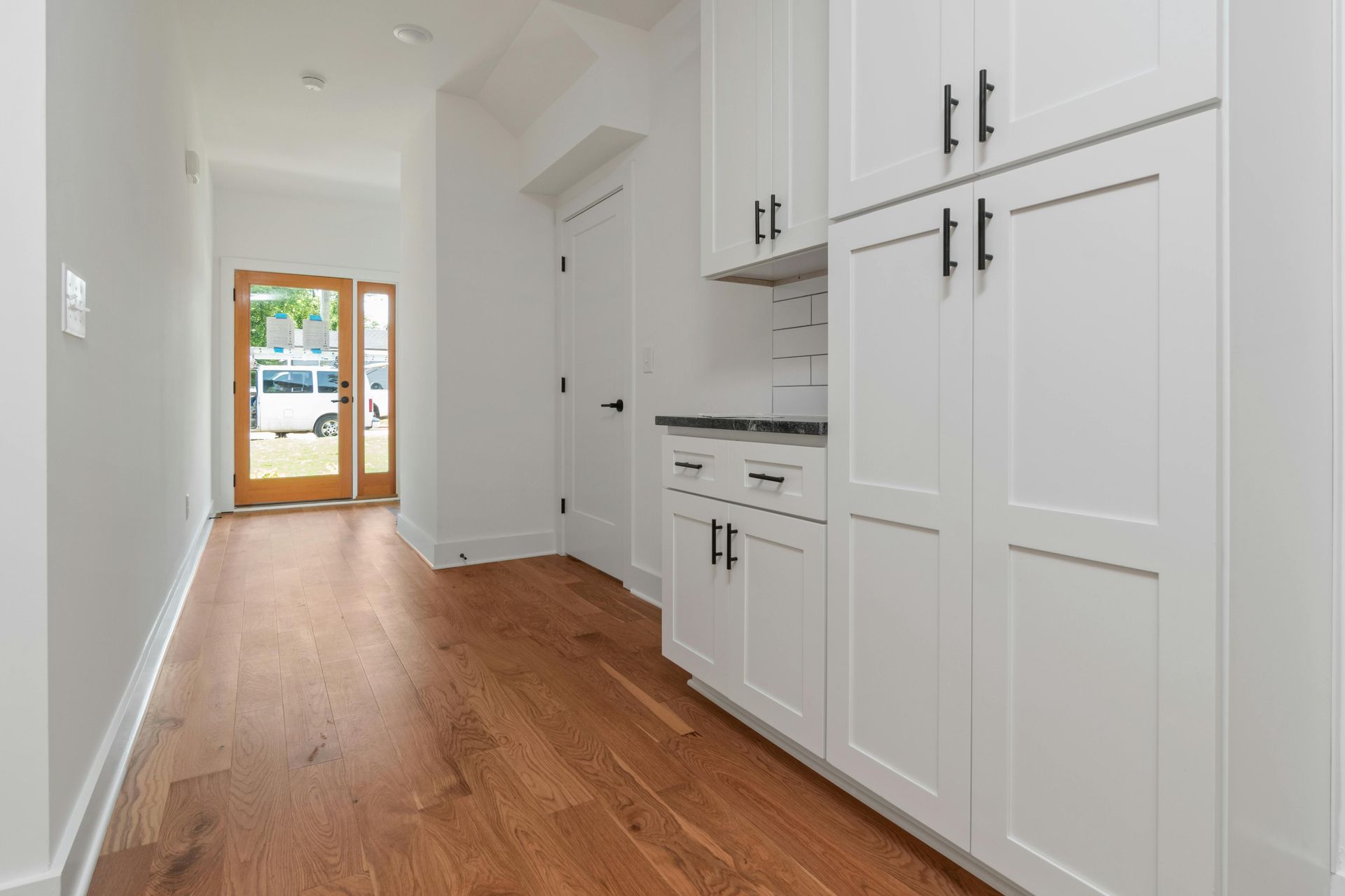 White shaker storage cabinets fitted along a hallway with a wood floor