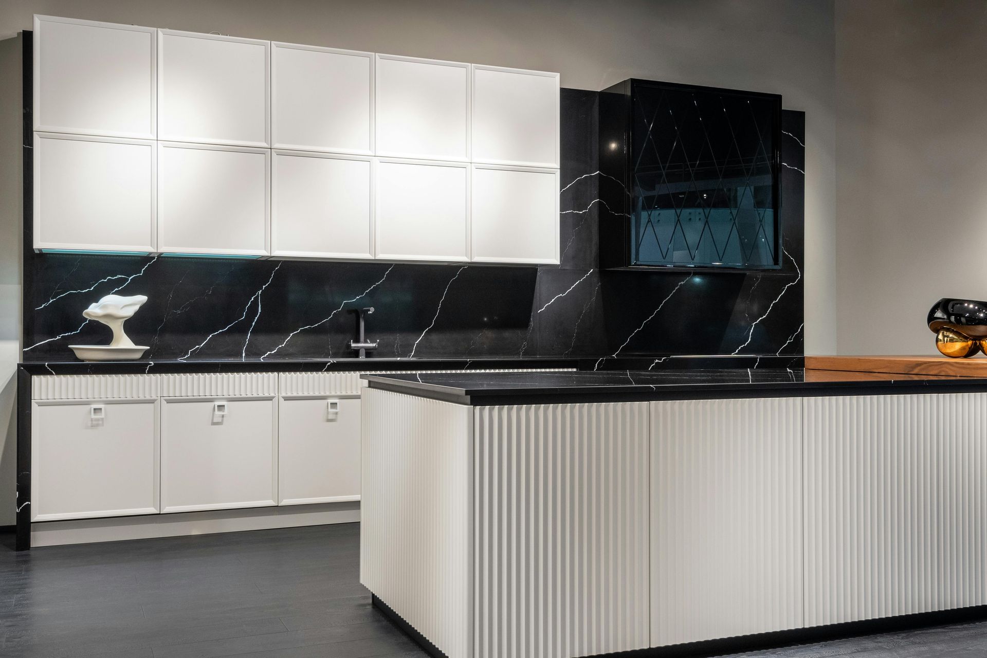 White and black marble kitchen cabinetry with a fluted island front